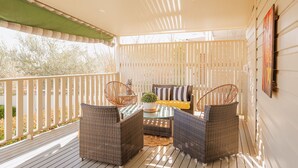 A covered outdoor seating area with wicker furniture, a glass table, and a potted plant. - Cozy Cottage with Kitchen & Patio (East Tamworth)