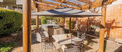 A covered outdoor patio with a grill, seating, and a pergola structure.