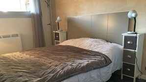 Ein Schlafzimmer mit einem Bett, einem Nachttisch, einer Lampe und einer Heizung.