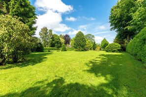 A well-maintained grassy area with various trees and shrubs, likely part of a park or garden setting. - Charming Normandy cottage with large garden, sheltered from the wind and 10' from the sea (Luneray)