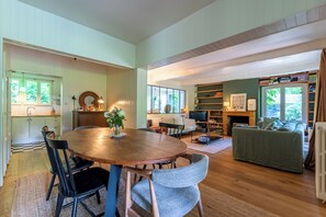 Un vaste espace de vie comprenant une table à manger en bois, des chaises, un canapé et une cheminée.