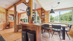 Un intérieur en bois comprenant un coin repas, une cuisine et de grandes fenêtres.