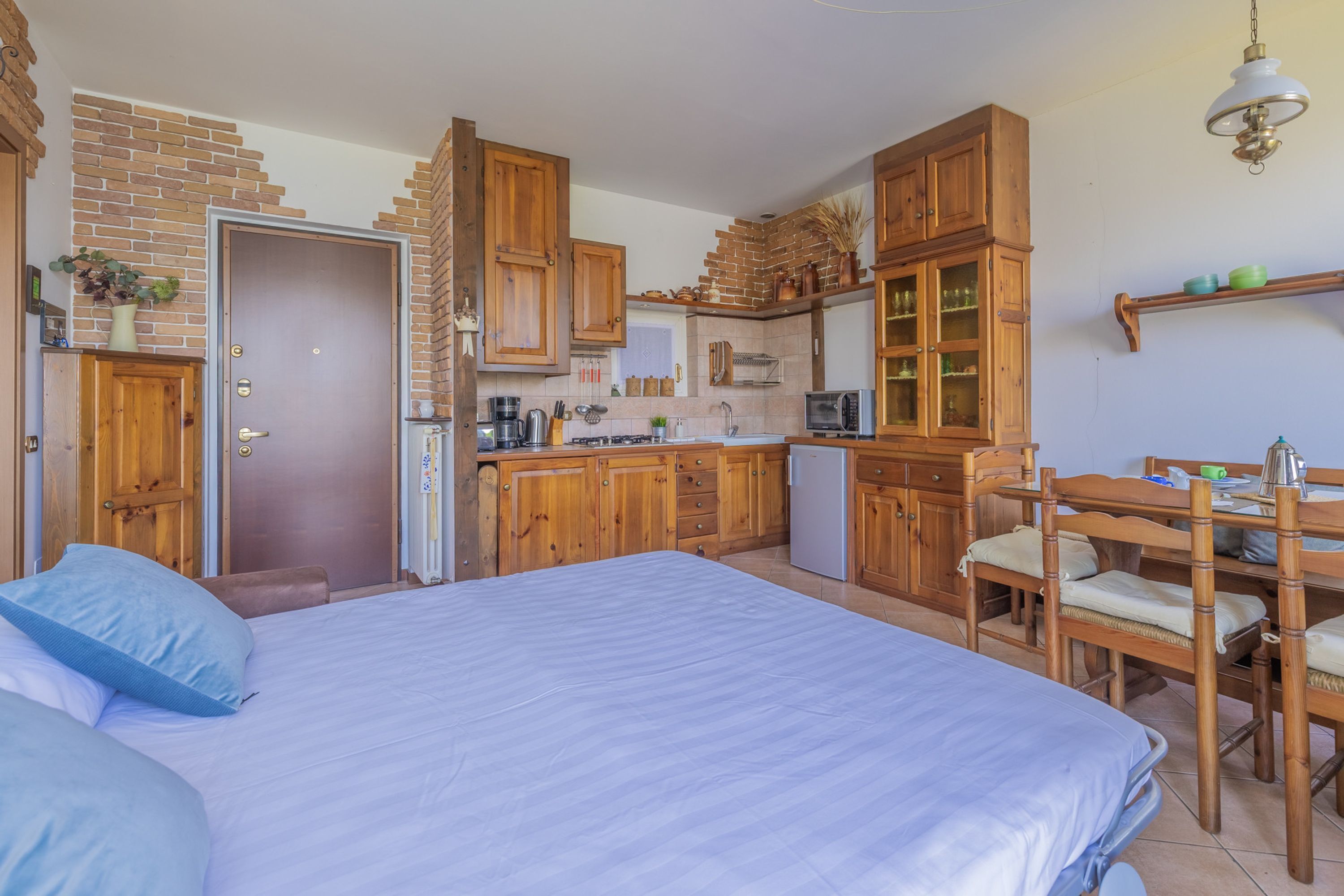 A compact room with a bed, a kitchenette, and a dining area.