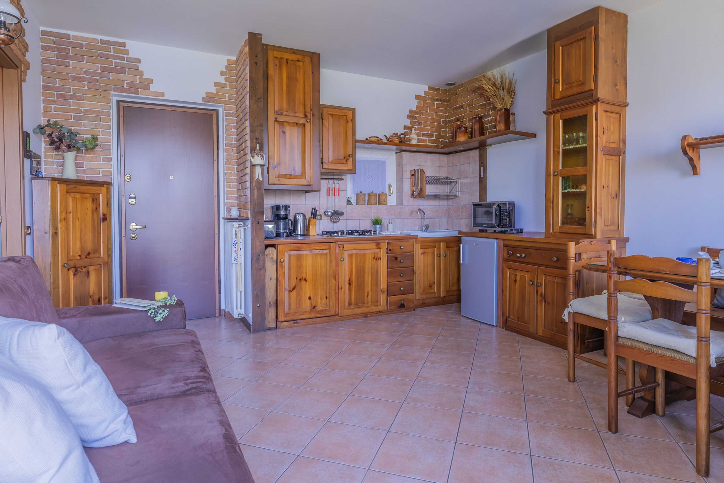 A kitchen with wooden cabinets, a dining area with a table and chairs, and a living room with a sofa.