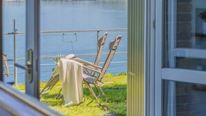 Udsigt over en sø med et bord og to stole på en balkon.