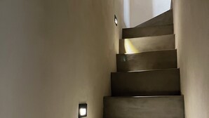 Una escalera con una lámpara en la pared y una sombra proyectada en los escalones.