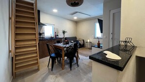 Una cocina compacta con comedor, estantes de madera y una lámpara en el techo.