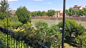 A river with a bridge, greenery, and buildings in the background. - Adige View Suite (Verona)