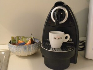 A coffee machine with a cup holder and a bowl of coffee pods. - Adige View Suite (Verona)