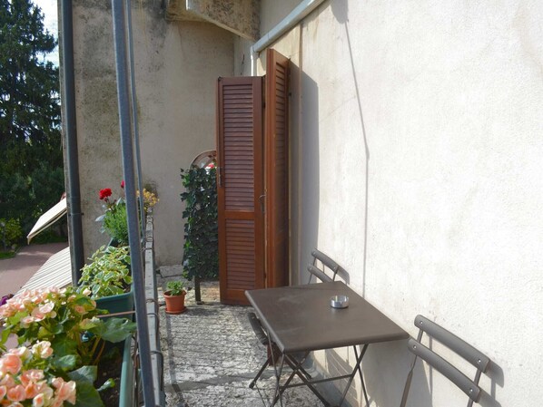 Un pequeño patio al aire libre con una mesa, sillas, una puerta de madera y plantas en macetas.