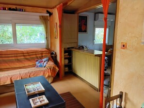 Une pièce confortable avec un lit, une petite table, un coin cuisine et une fenêtre.