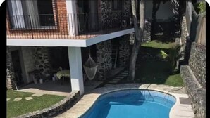 Une piscine à bord incurvé, un mur en pierre et un hamac.