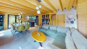A modern interior with a dining area, sofa, and wooden ceiling. - Cosy chalet with jacuzzi for 11 (Bonnevaux)