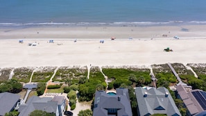Eine Küstenimmobilie mit Blick auf den Strand, mehreren Schwimmbecken und einem Parkplatz.