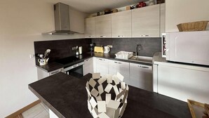 Cocina moderna con encimeras oscuras, armarios blancos y una campana extractora de acero inoxidable.