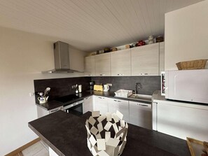 Eine moderne Küche mit dunklen Arbeitsplatten, weißen Schränken und einer Edelstahl-Dunstabzugshaube.
