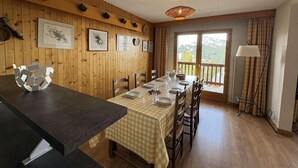 Comedor con una mesa dispuesta para cuatro, paredes de paneles de madera, un ventanal y una lámpara.