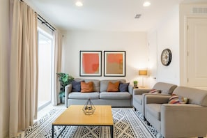 Ein Wohnzimmer mit einer Couch, einem Couchtisch und zwei gerahmten Kunstwerken an der Wand.