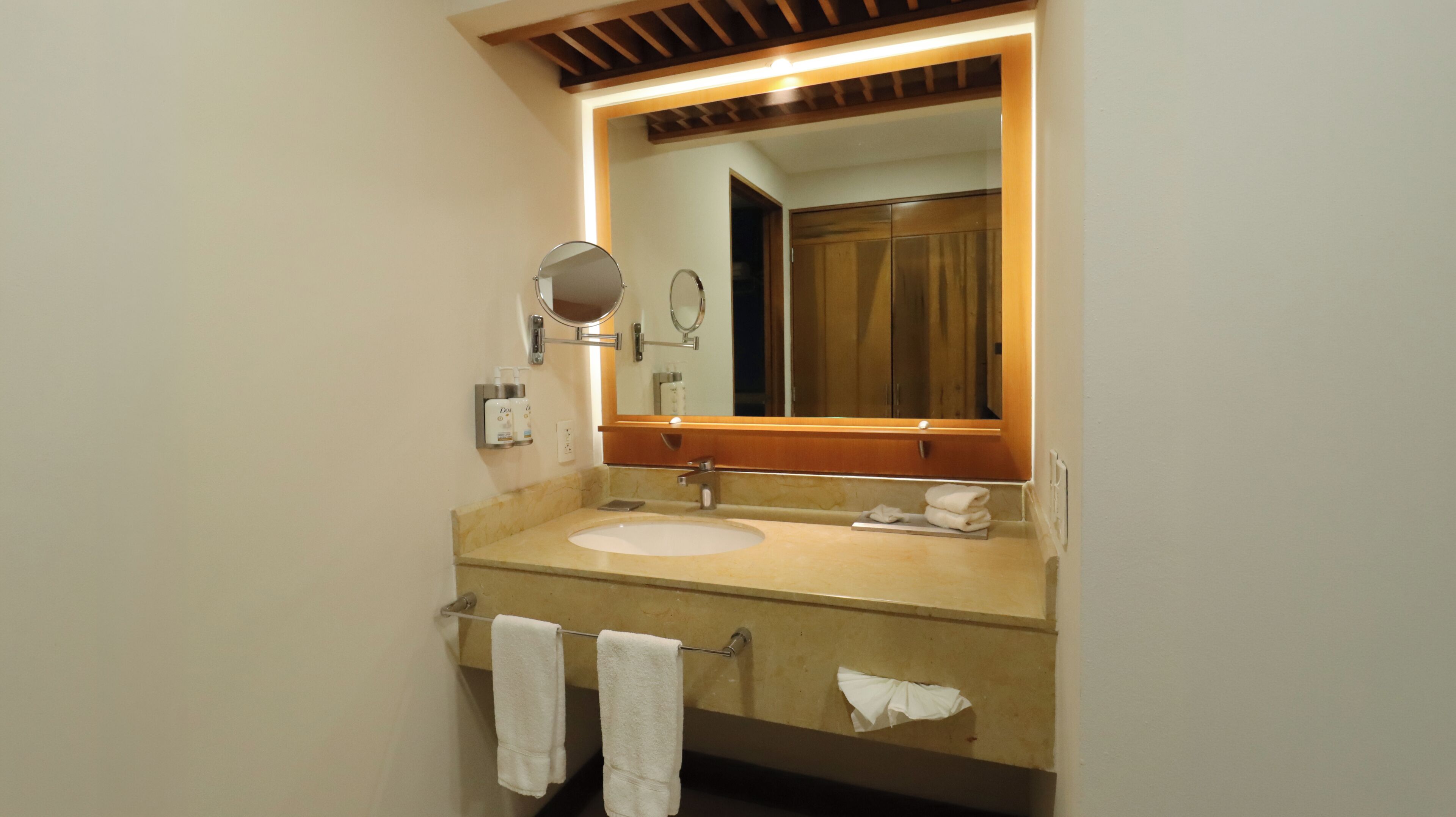 A bathroom with a sink, mirror, towel rack, and a wooden ceiling.