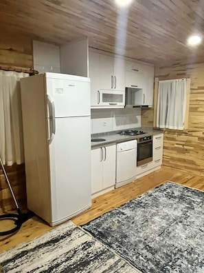 A compact kitchen with white appliances, wooden walls, and a patterned rug. - Karatay Villas with AC and swimming pool in charming Demre (Demre)