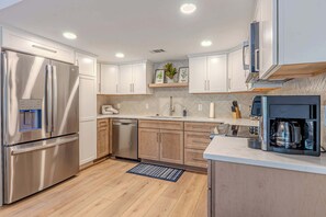 Una cocina moderna con electrodomésticos de acero inoxidable, armarios de madera y una cafetera integrada.