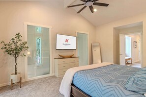 A bedroom with a bed, a ceiling fan, a TV, a wooden dresser, a plant, and a sliding glass door. - 3BR Shipmaster Suite (Hilton Head Island)