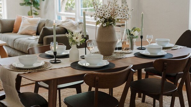 A dining area with a wooden table set for four, surrounded by chairs, with a vase of flowers and candles on the table. - š Designer Bird Rock Gem | Walk to Beach & Cafe (La Jolla)