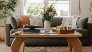 A living room with a sofa, a coffee table, a vase with flowers, a chessboard, and a few books. - š Designer Bird Rock Gem | Walk to Beach & Cafe (La Jolla)