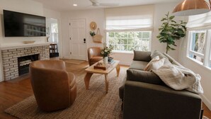 A living room with a fireplace, leather chairs, a sofa, a coffee table, and a television. - š Designer Bird Rock Gem | Walk to Beach & Cafe (La Jolla)