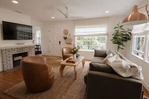 A living room with a fireplace, leather chairs, a sofa, a coffee table, and a television. - 🌊 Designer Bird Rock Gem | Walk to Beach & Cafe (La Jolla)