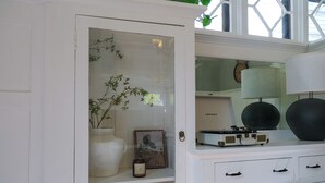 A white cabinet with a glass door, a framed picture, a candle, and a small chessboard. - 4BR Hygge Home | Theater + Game Room | Sleeps 10 (Minneapolis)