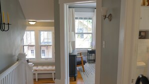 A hallway with a bench, a lamp, and a view of a room with a window. - 4BR Hygge Home | Theater + Game Room | Sleeps 10 (Minneapolis)