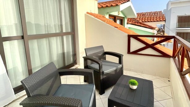 Ein Balkon mit Korbm öbeln, einem kleinen Tisch und einem Blumentopf.