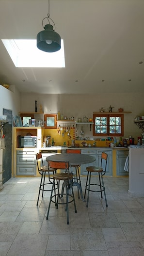 Une cuisine dotée d’une lucarne, d’une table à manger avec des chaises et de divers appareils de cuisine.