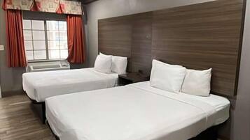 Ein Hotelzimmer mit zwei Betten, einem großen Fenster mit Vorhängen und Holzboden.