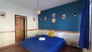 Habitación de hotel con cama, puerta y pared azul con cuadros.