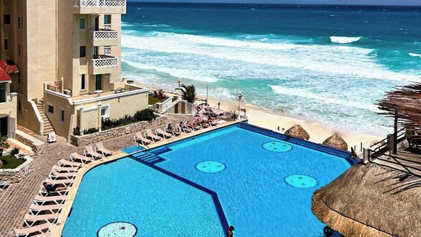 Un hotel con piscina, vista sulla spiaggia e un edificio con balconi.