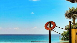 Vista sulla spiaggia con tetto di paglia, un salvagente e cielo azzurro.