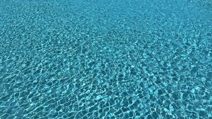 Una piscina cristallina con vista sull'oceano e una postazione di salvataggio.
