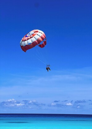 A parasail with a red and white canopy over the ocean. - OCEAN FRONT APARTMENTS CANCUN (cancun)