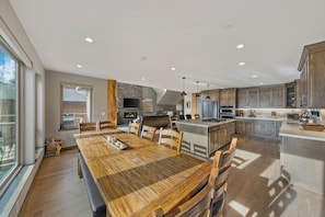 A spacious kitchen with wooden cabinetry, a central island, and a dining area with a large wooden table and chairs.