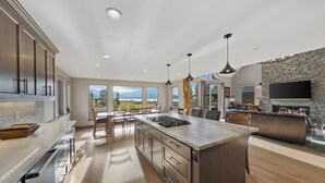 A modern kitchen with a large island, stainless steel appliances, and a stone fireplace. - 7 bedroom Luxury by the Lake (South Lake Tahoe)