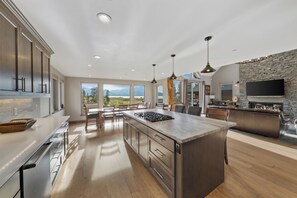 A modern kitchen with a large island, stainless steel appliances, and a stone fireplace.