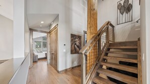 A wooden staircase with a railing, a hallway with wooden flooring, and a door leading to a room with a bed. - 7 bedroom Luxury by the Lake (South Lake Tahoe)