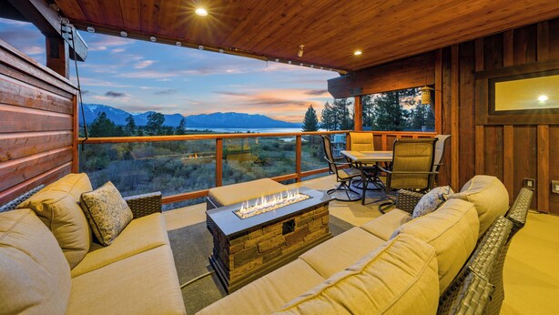 A cozy wooden cabin with a large window, a fire pit, and a seating area. - 7 bedroom Luxury by the Lake (South Lake Tahoe)