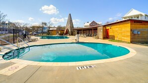 Piscina com um deck ao redor, um mastro de bandeira e uma estrutura cónica marcante ao fundo.