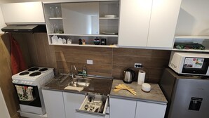 Cocina pequeña equipada con estufa, fregadero, microondas y refrigerador.