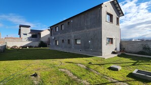 Un edificio moderno con techo plano, patio cubierto de césped y cielo despejado.