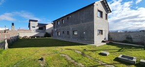 A modern building with a flat roof, a grassy courtyard, and a clear sky. - Mayim Lodging: Comfort and Relaxation in Sarmiento, Chubut, Argentina (Sarmiento)