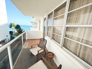 A balcony with a chair, a small table, and a view of the ocean. - Elegant 1BR Oceanfront Retreat Sleeps 6 (Hollywood)